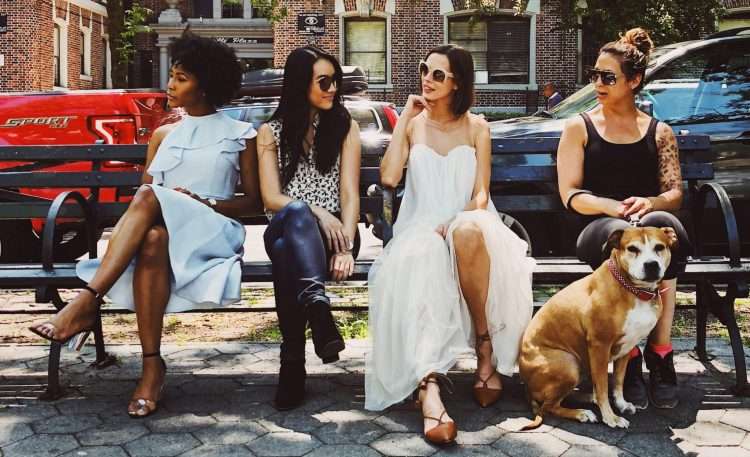 four women sitting on black steel bench during daytime