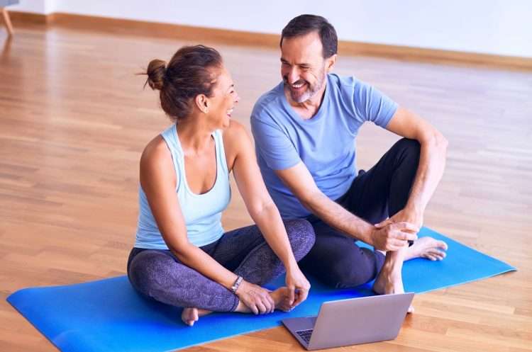 man in white tank top and gray pants sitting on blue yoga mat