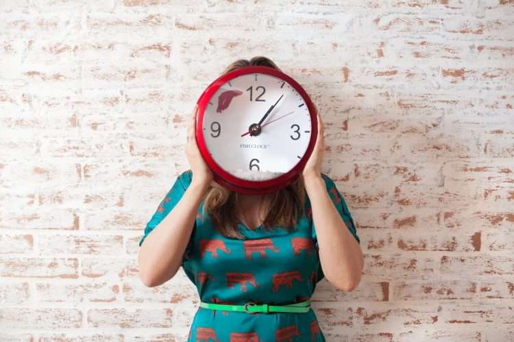 woman covering her face with a clock
