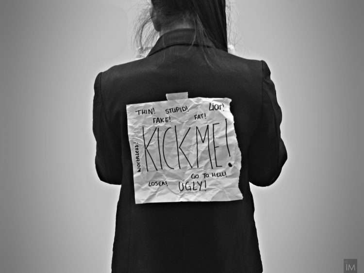 photo of a bullied women with a kick me sign on her back