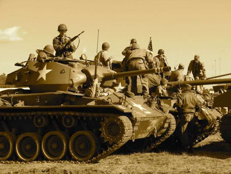 people sitting and standing on battle tank during a war