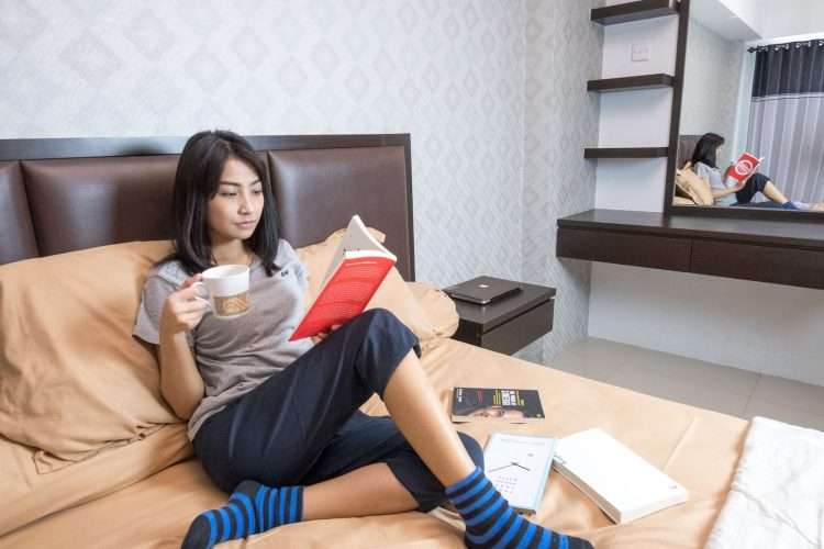 woman on a bed reading and drinking coffee