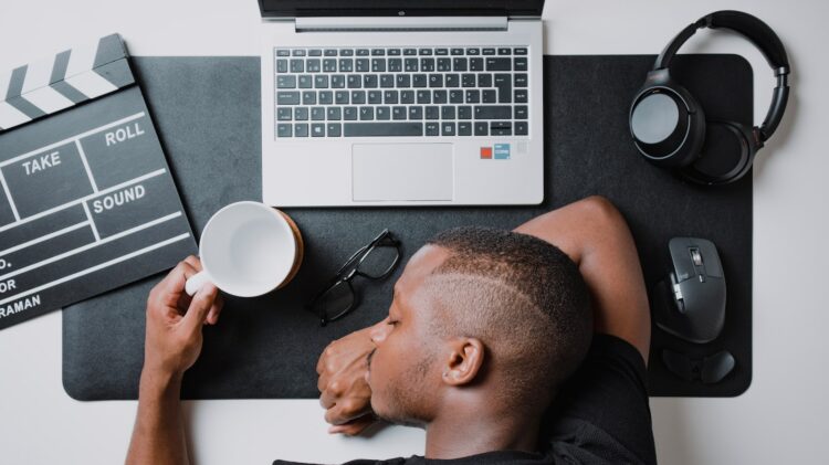 a man sitting at a desk with a laptop and headphones procrastinating